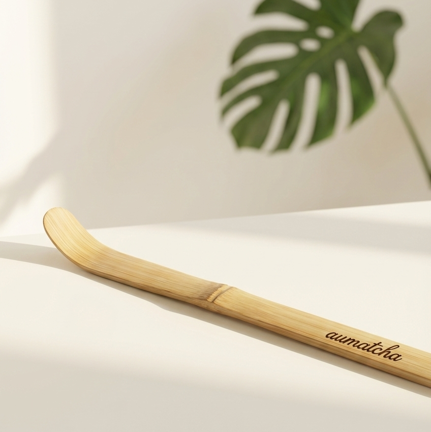 Bamboo spoon with 'aumatcha' branding on a light background